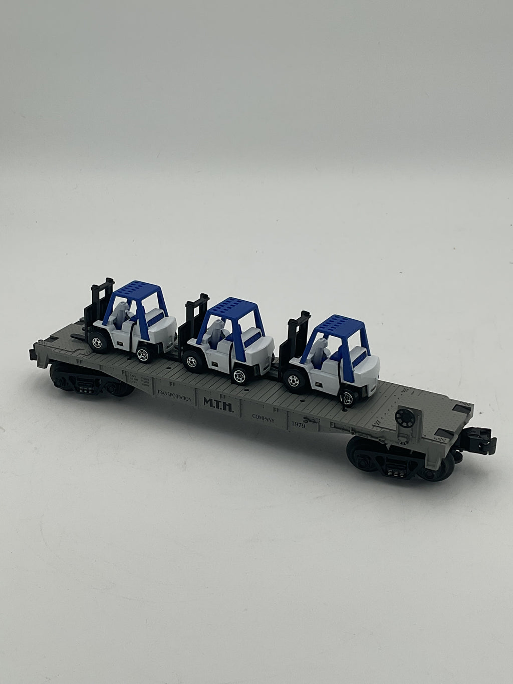 MTH 1979T-205 Custom MTH Transportation Company Flat Car w/ 3 Blue-White Forklifts Plus Extra Forklift w/Driver by The Train Loft